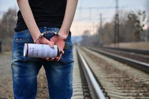 Girl in handcuffs with spraycan on the background of a railway t photo