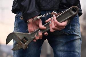 The girl in handcuffs with the adjustable wrench on the railway track background. The concept of crime prevention with the participation of the railway and trains. photo