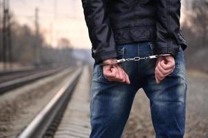 chica esposada en el fondo de una vía férrea. el concepto de prevención del delito con la participación del ferrocarril y los trenes. foto nocturna de la mitad inferior del cuerpo de una niña