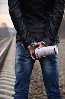 Girl in handcuffs with spraycan on the background of a railway track. The concept of vandalism prevention with the participation of the railway and trains. photo