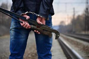 The girl in handcuffs with the pipe wrench on the railway track photo