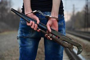 The girl in handcuffs with the pipe wrench on the railway track photo