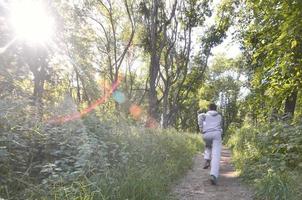 A young guy in a gray sports suit runs along the path among the photo