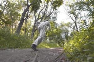 A young guy in a gray sports suit runs along the path among the photo