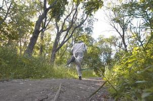 A young guy in a gray sports suit runs along the path among the photo