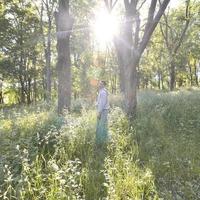 A young guy in a gray sports suit stands opposite the sun among photo