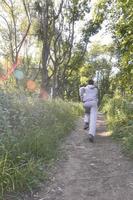 un joven con un traje deportivo gris corre por el camino entre los foto