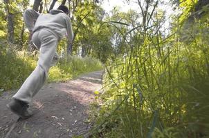 A young guy in a gray sports suit runs along the path among the photo