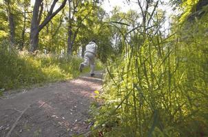 A young guy in a gray sports suit runs along the path among the photo