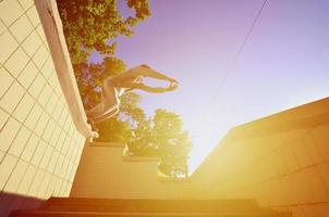 A young guy performs a jump through the space between the concrete parapets. The athlete practices parkour, training in street conditions. Bottom view photo