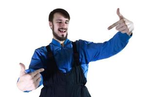 A young bearded guy in working uniform points to himself with his two hands. A proud worker takes praise and encouragement to his person. Isolated on white photo