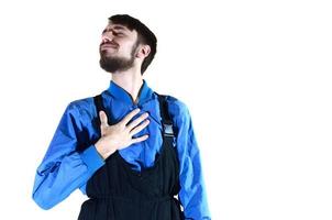 A young bearded guy in working uniform points to himself with his hand. A proud worker takes praise and encouragement to his person. Isolated on white photo