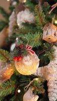 Vertical video, Unrecognizable Girl Decorates a Christmas Tree with Festive Balls. Warm Lights from Garlands Flicker in the Background. Holiday New Year. Winter Atmosphere, Tradition Concept. video