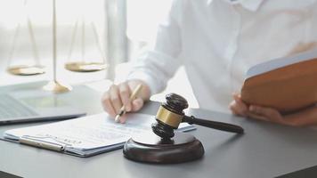 Business and lawyers discussing contract papers with brass scale on desk in office. Law, legal services, advice, justice and law concept picture with film grain effect video