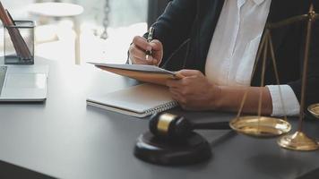 Business and lawyers discussing contract papers with brass scale on desk in office. Law, legal services, advice, justice and law concept picture with film grain effect video