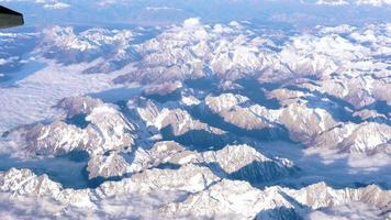 Beautiful view through airplane window, airplane flying above the mountains with clouds. China territory. video