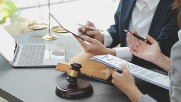 Business and lawyers discussing contract papers with brass scale on desk in office. Law, legal services, advice, justice and law concept picture with film grain effect video