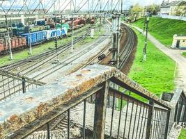 ferrocarril en la ciudad. camino viejo y oxidado debajo del puente. las barandillas del puente están pintadas con pintura y cubiertas de óxido. rieles de metal foto