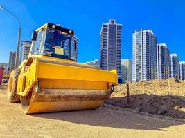 construcción de un nuevo microdistrito en el centro de la ciudad. edificios altos de varios pisos hechos de hormigón y vidrio. junto a la casa excavadora amarilla para la construcción foto