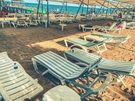 Sunbeds chaise longue at tropical empty beach and turquoise sea - Panorama of dream vacation in exclusive destination with white sand in a sunny beautiful day. photo