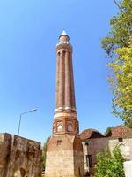 area in tropical country. against the backdrop of a blue sky stands a tall tower made of stone and clay. a tower with windows and a spire at the top on a large foundation photo
