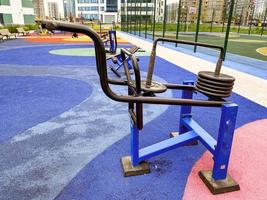 metal trainers on the street. workout area for outdoor sports. entertainment for adults and children. weight training machine with metal pancakes photo