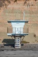 torre de salvavidas vacía en la playa con montaña en el fondo foto