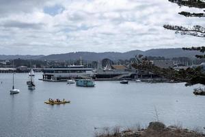 People canoeing and boats on sea with scenic view of mountains and cloudy sky photo