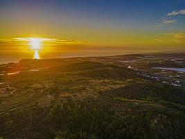 vista aérea de la puesta de sol sobre las tierras de cultivo y el mar foto