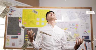 Portrait of successful asian businessman throwing banknotes in office. Happy rich millionaire throws cash. Confident male manager celebrating victory with cash. video