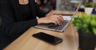 Closeup side view of hands typing on keyboard laptop pc while sitting at workplace desk in office room. Businesswoman wearing formal suit. woman working on computer notebook. video