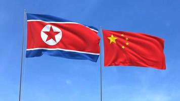Waving flags of North Korea and China on blue sky background video