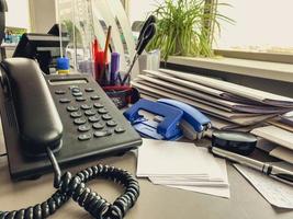 landline phone in the office on the table. black handset with buttons and display. communications in the office photo