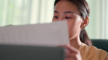 Selective focus, Close up shot young woman seriously while checking on graph or analytics report and typing on laptop computer, new normal and working from home concept video