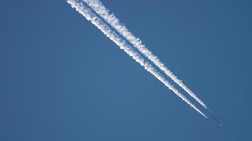 Aircraft flying by high in the sky leaving thick contrail behind it video