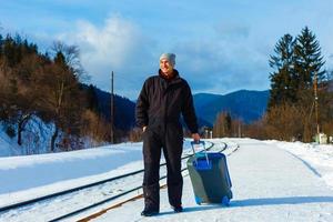 man in winter clothes standing on the platform of a train station photo