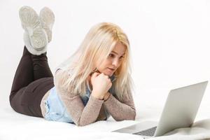una chica cansada está tirada en el suelo con una laptop foto