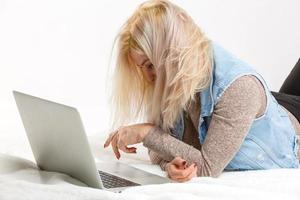 una chica cansada está tirada en el suelo con una laptop foto