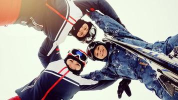 Group of happy skiers and snowboarders stands in circle and smiling photo