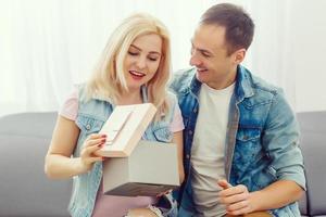 Love, holiday, celebration and family concept - smiling man surprises his girlfriend with present at home photo