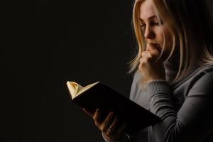 A young woman in prayer under dramatic light. photo