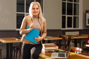 concepto de aprendizaje electrónico con un estudiante que sostiene su computadora portátil moderna, el tutor debe ser entusiasta y debe gustarle su materia, el maestro dibuja en el aula de la escuela, foto