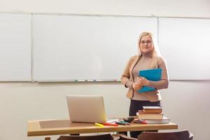 concepto de aprendizaje electrónico con un estudiante que sostiene su computadora portátil moderna, el tutor debe ser entusiasta y debe gustarle su materia, el maestro dibuja en el aula de la escuela, foto