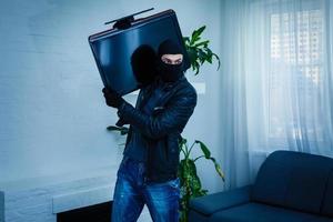 Man burglar stealing tv set from house photo