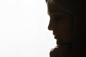 una mujer joven en oración bajo una luz dramática. foto