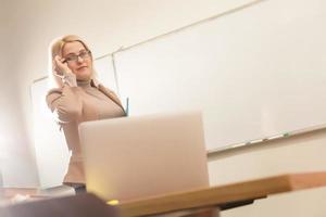 concepto de aprendizaje electrónico con un estudiante que sostiene su computadora portátil moderna, el tutor debe ser entusiasta y debe gustarle su materia, el maestro dibuja en el aula de la escuela, foto