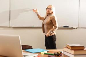 Portrait of pretty teacher holding notepads in a classroom in school photo