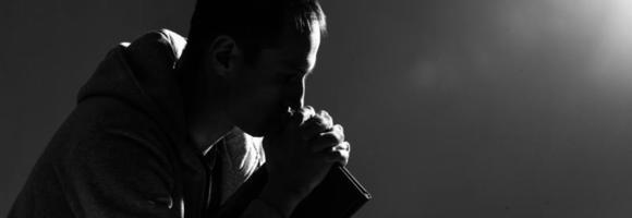 Religious young man praying to God on dark background, black and white effect photo