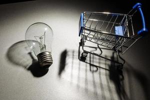 Shopping cart with light bulb on black background. photo