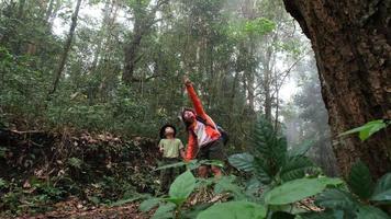 mujer joven feliz con su hija caminando juntos en un viaje de campo en las montañas. familia en una aventura de senderismo por el bosque. los padres enseñan a sus hijos sobre la naturaleza y las plantas. video